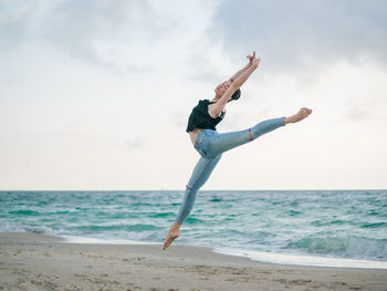 Full length of woman ballet dancing at beach