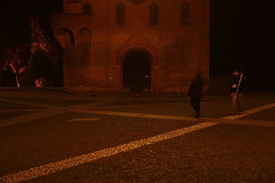 Rear view of silhouette man walking at illuminated temple