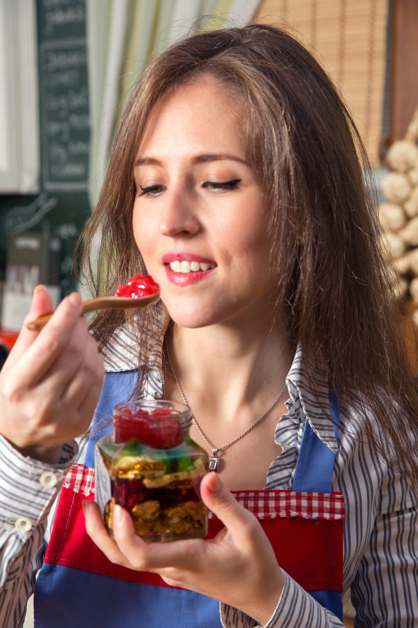 PORTRAIT OF YOUNG WOMAN HOLDING ICE CREAM IN SHOP