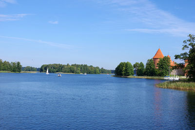 Scenic view of river by buildings against blue sky