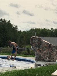 Side view of shirtless man in swimming pool against sky