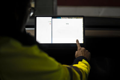 Male electric vehicle technician programming on digital tablet in car