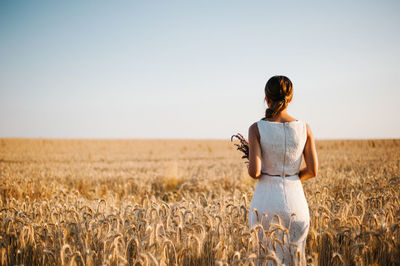 Woman standing in field against clear sky