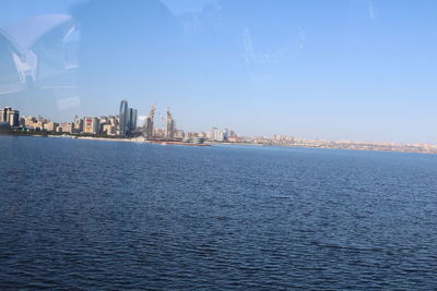 Sea by buildings against sky in city