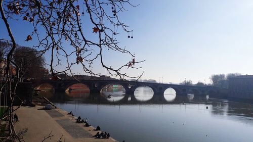 Bridge over river in city against clear sky