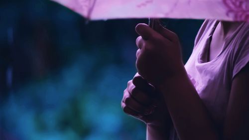 Cropped image of woman holding umbrella during rainy season