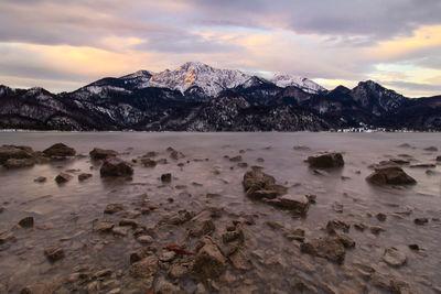 Scenic view of snowcapped mountains and kochelsee against sky  during sunset
