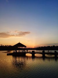 Silhouette bridge over river against sky during sunset