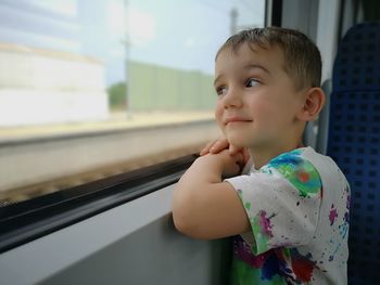 Side view of boy looking through window in train