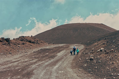People on arid landscape against sky
