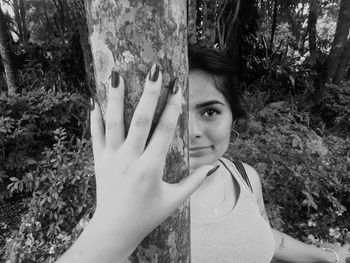 Portrait of young woman against tree trunk