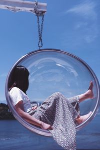 Rear view of woman holding umbrella against blue sky