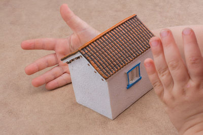 High angle view of person holding model home on table