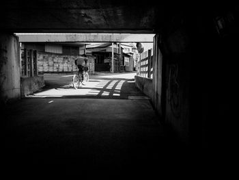 Rear view of woman walking in alley amidst buildings in city