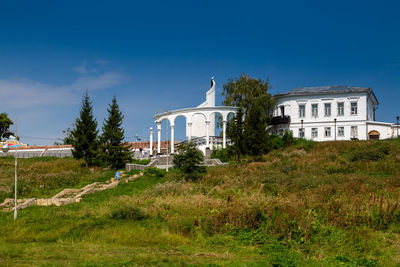 House on field against clear blue sky