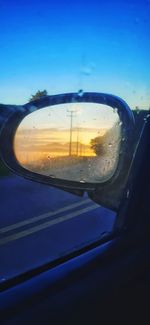 Reflection of car on side-view mirror at sunset