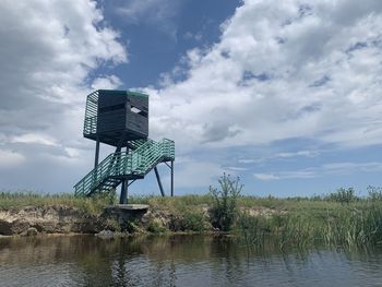 Lifeguard hut by lake against sky