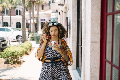 Woman eating ice cream while standing in city