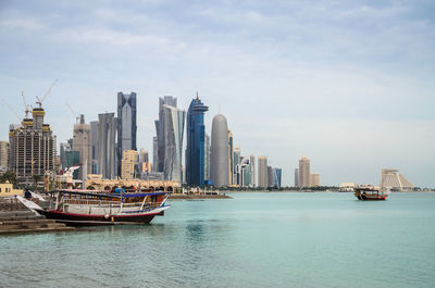 Boats in sea by buildings against sky