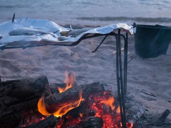 Close-up of campfire at sandy beach