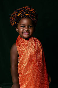 Portrait of smiling boy standing against black background