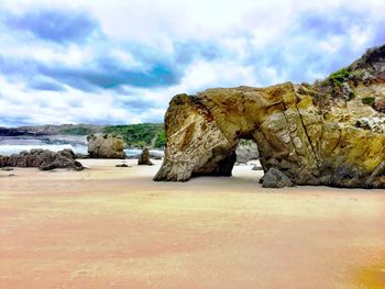 Rock formations on beach against sky