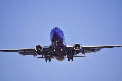 Low angle view of airplane against clear blue sky