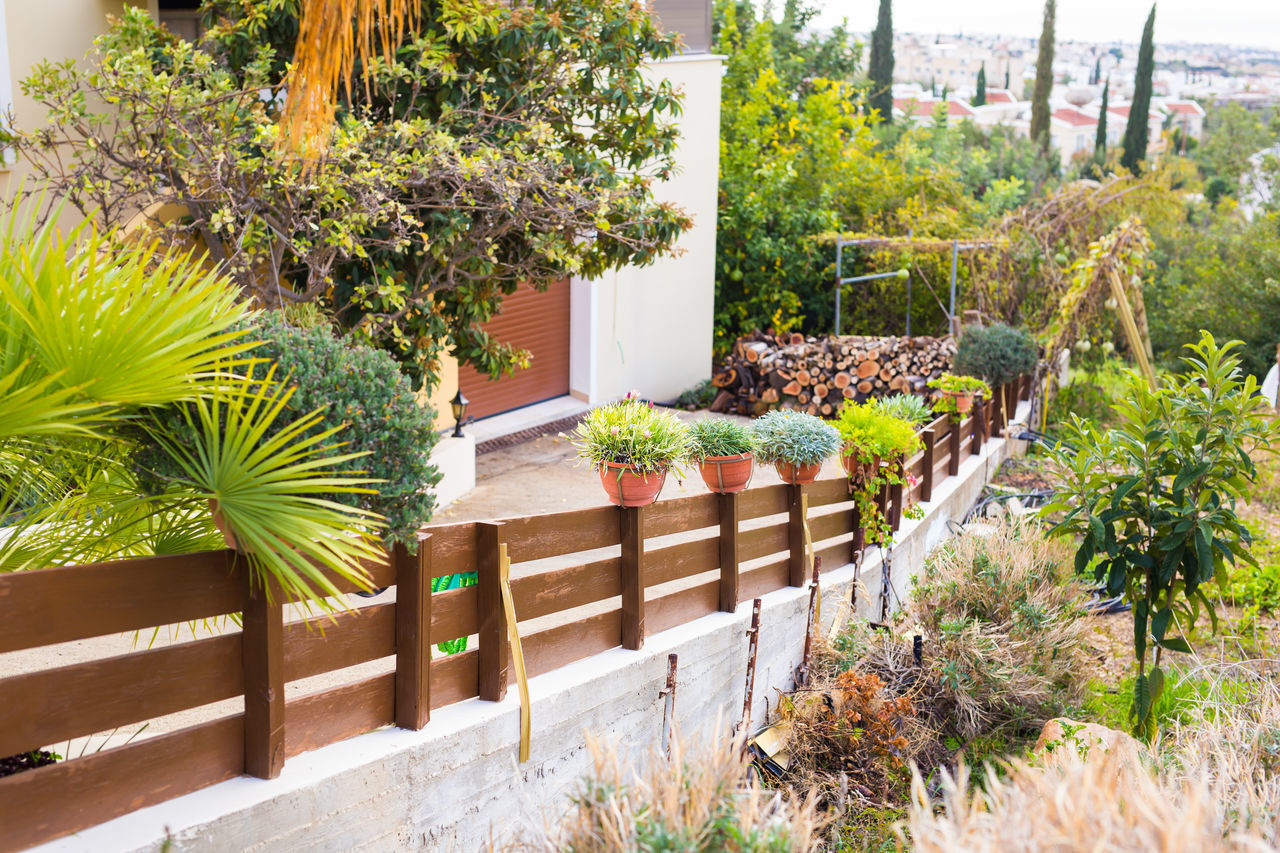 HIGH ANGLE VIEW OF POTTED PLANTS BY RAILING AGAINST TREES