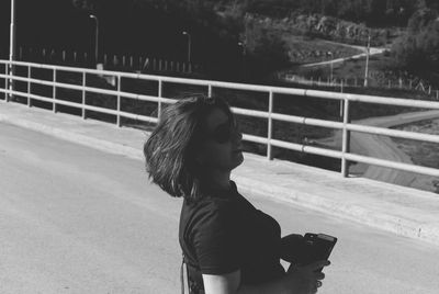 Side view of woman looking away while standing on road