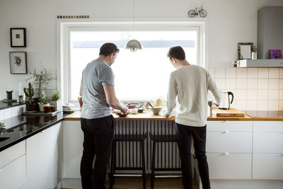 Rear view of father and son preparing food in kitchen at new house