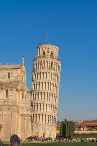 People at historical building against blue sky