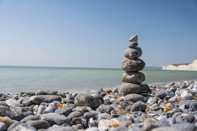 Stack of pebbles on beach against sky
