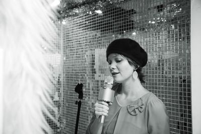 Young woman singing while holding microphone against net