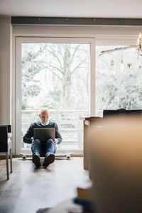 Senior man sitting on ground, using laptop