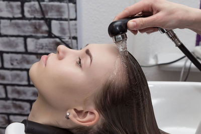 Cropped hand washing woman hair in salon