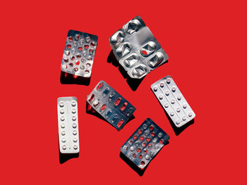 Top view of various empty blister packs of pills for health care placed on red background in light studio during health treatment