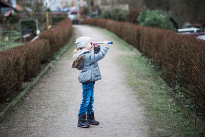 Rear view of boy using mobile phone on road