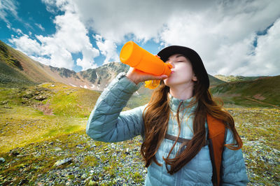 Woman takes a break to drink from a water bottle while hiking. young hiker drinks water in a