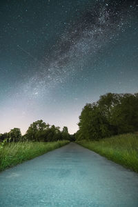 Road amidst trees against sky at night