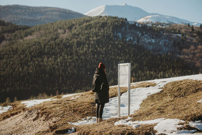 Woman tourist hiker checking the mountain trail route on the board