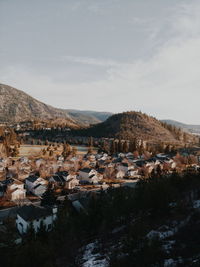 Scenic view of townscape by mountains against sky