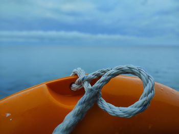 Close-up of rope tied on sea against sky