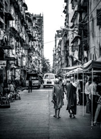 Rear view of people walking on street in city