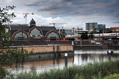 Bridge over river by buildings against sky