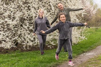 Family having fun with flowering tree in blooming spring garden