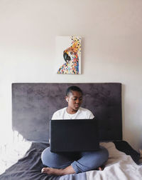 Woman using laptop while sitting on bed at home