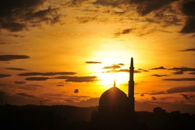 Silhouette mosque against orange sky