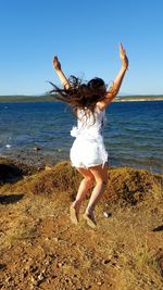 Young woman on beach against clear sky