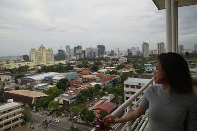 Woman standing by buildings in city against sky