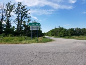 Road by trees against sky